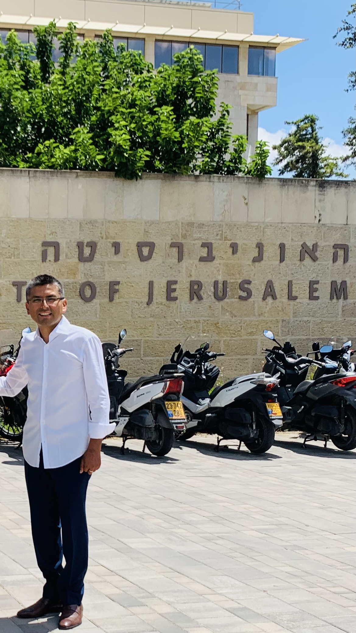 Man in a white shirt standing in front of a sign in Jerusalem